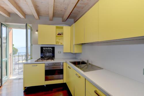 a kitchen with yellow cabinets and a large window at Magic apartment with view on Garda lake in the center of Desenzano in Desenzano del Garda