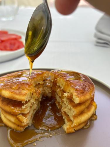 a spoon is pouring syrup onto a stack of pancakes at Hostel & Camping Rilindja in Valbonë