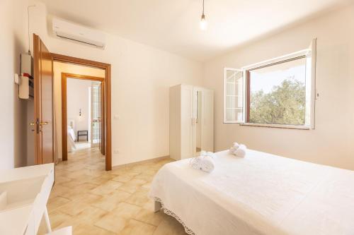 a white bedroom with a large bed and a window at Villa Dolcevivere in Specchiolla 