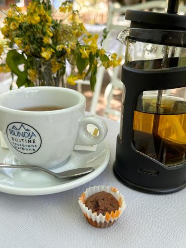 a cup of coffee and a cupcake on a table at Hostel & Camping Rilindja in Valbonë