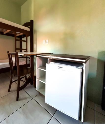 a refrigerator in a room with a table and a chair at Hotel Girassol in Imbé