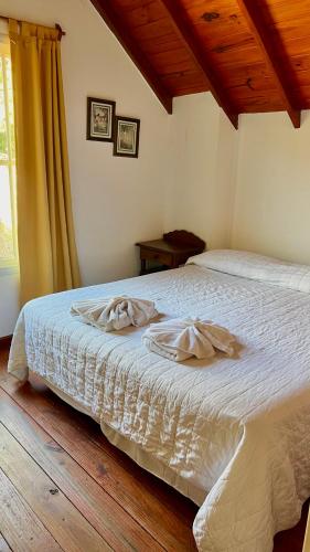 a bedroom with a bed with white sheets and a window at Tata Inti Complejo Serrano in Merlo