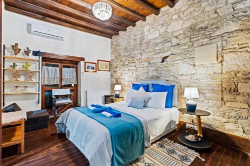 a bedroom with a bed and a stone wall at RedBlue Door Two Traditional Listed Houses in Pano Lefkara