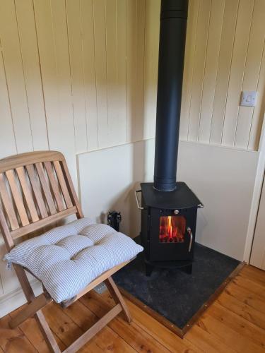 a chair and a wood stove in a room at Shepherd's Hut in heart of the Brecon Beacons in Bwlch