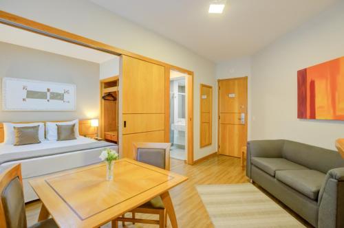 a room with a bed and a couch and a table at Hampton Park São Paulo Jardins in Sao Paulo