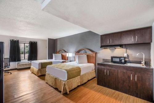 a hotel room with two beds and a kitchen at Hotel O Orlando Airport near Florida Mall in Orlando