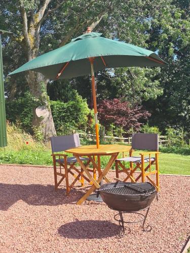 a picnic table and two chairs under an umbrella at Shepherd's Hut in heart of the Brecon Beacons in Bwlch