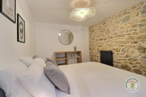 a bedroom with a white bed and a stone wall at Juliette in Saint-Georges-de-Chesné