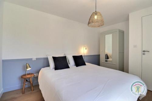 a bedroom with a large white bed with black pillows at Juliette in Saint-Georges-de-Chesné