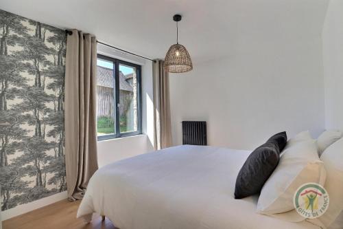 a bedroom with a white bed and a window at Juliette in Saint-Georges-de-Chesné
