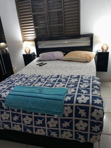 a bedroom with a bed with a blue and white comforter at Gama empreendimentos in Campo Grande