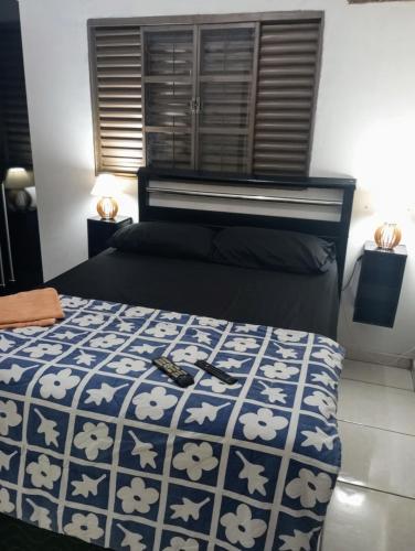 a bedroom with a bed with a blue and white comforter at Gama empreendimentos in Campo Grande