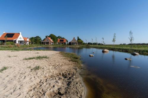 a river with ducks in the water next to houses at Hello Zeeland - Vakantiewoning Knuitershoek 88 in Kloosterzande