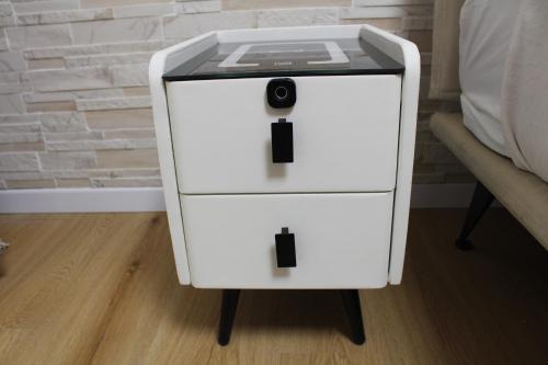 a white night stand with a drawer next to a bed at Argenta Center every comfort in Argenta