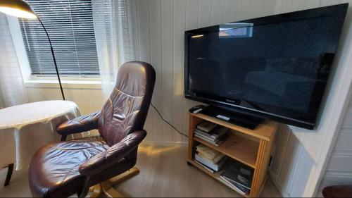 a leather chair sitting in front of a television at Romslig ferieleilighet nær sjøen Medby Senja in Senja