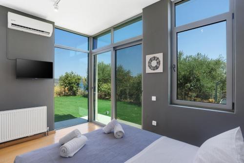 a bedroom with two towels on a bed with a large window at Villa Seaview Serenity - Jacuzzi & Panoramic Views in Chania
