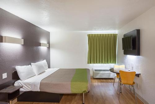a small room with a bed and a green window at Studio 6 Fort Worth, TX - Meacham in Fort Worth