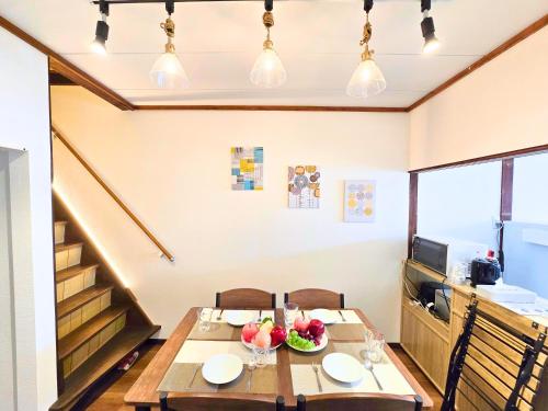 een eetkamer met een tafel en een trap bij Osaka Riverside Inn in Neyagawa