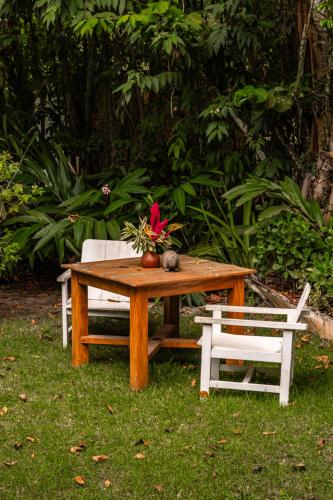 a wooden table with two chairs and a red flower on it at Hotel Boutique Bahia Bonita in Trancoso