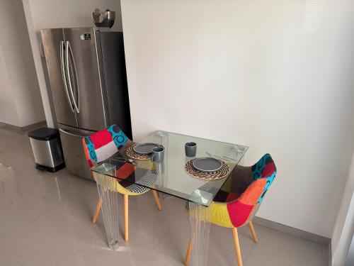 a glass table with chairs and a stainless steel refrigerator at Blissful Bubali Apartment Aruba in Palm-Eagle Beach
