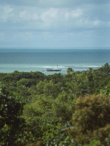 a boat in the water near the ocean at Hotel Boutique Bahia Bonita in Trancoso