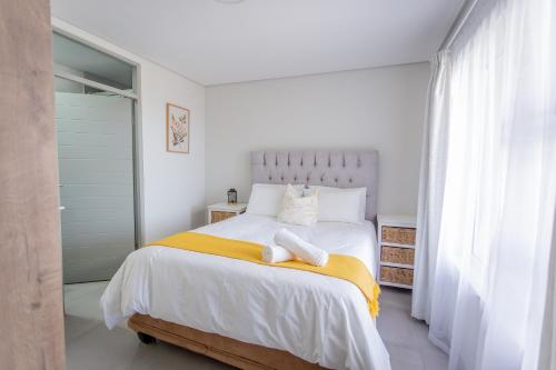 a white bedroom with a large bed with yellow blanket at Luxury Apartment - Apartment 44 - 1 On York in George