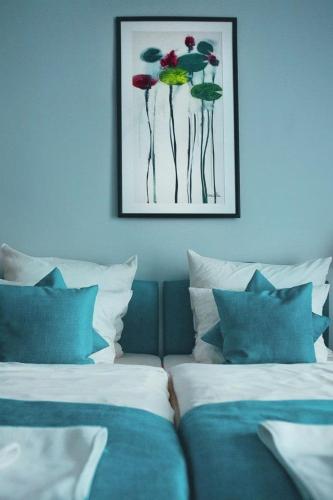a bed with blue and white pillows and a picture on the wall at Pałac Brunów - Wellness & SPA in Lwówek Śląski
