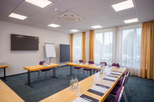a conference room with tables and chairs and a screen at Hotel Bessunger Forst in Roßdorf