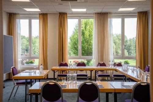 a conference room with tables and chairs and windows at Hotel Bessunger Forst in Roßdorf