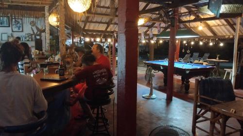 a group of people sitting at a bar with a pool table at Water's Edge Resort , in Panwa Beach