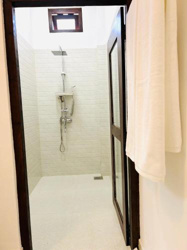 a shower with a glass door in a bathroom at Coco and Corks Villa in Negombo