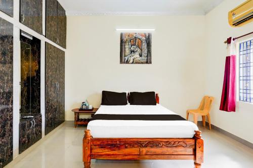 a bedroom with a wooden bed in a room at Hotel O Enclave Stayz Inn in Chennai
