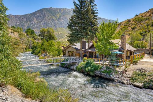 a bridge over a river in front of a house at Provo River Cabin with Private Bridge and Trail Access in Provo