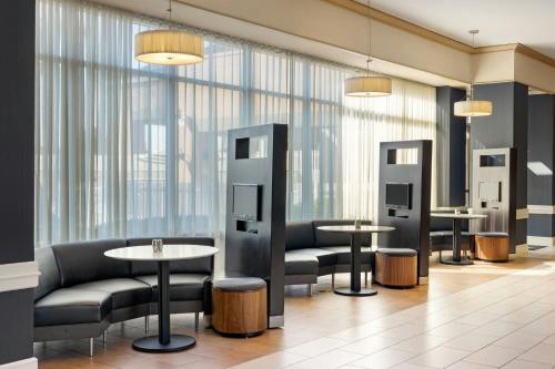a waiting room with tables and chairs and windows at Courtyard by Marriott Baldwin Park in Baldwin Park