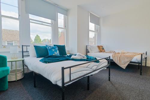 a bedroom with two beds and two windows at Group Stay Paradise 7 Bedrooms, All with En-Suites in Canterbury