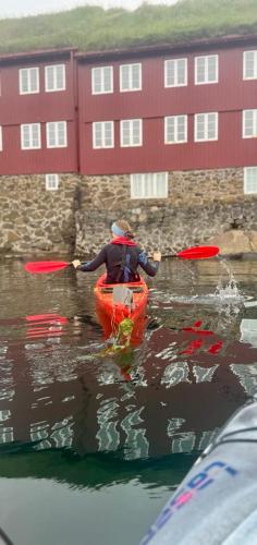 a person in a kayak in the water near a building at Luxury Boat House in City Center in Tórshavn