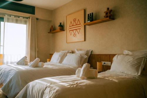 two beds in a room with white sheets at Flooka Surf & Yoga in Imsouane