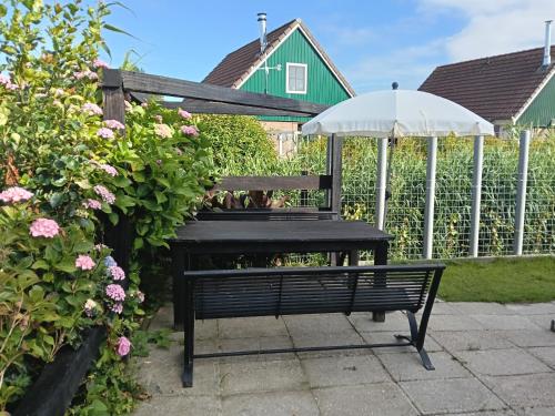 a bench with an umbrella next to a fence at 't Zijper Eilant 98 in Oudesluis