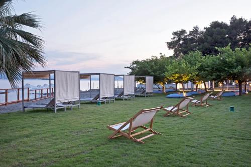 a group of chairs sitting on the grass near the water at Eretria Hotel & Spa Resort in Eretria