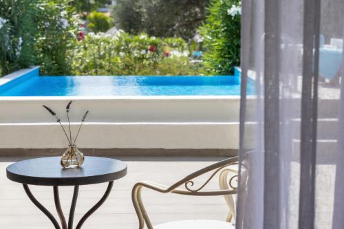 a table and chair next to a window with a pool at Eretria Hotel & Spa Resort in Eretria