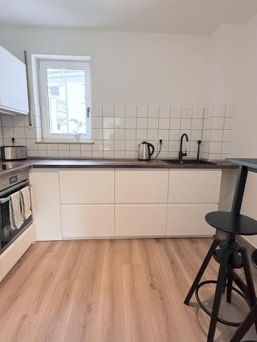 a kitchen with white cabinets and a wooden floor at Apartmenthaus Gilden 1 in Borken