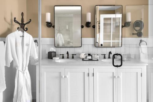 a white bathroom with two sinks and two mirrors at Pickering House in Wolfeboro