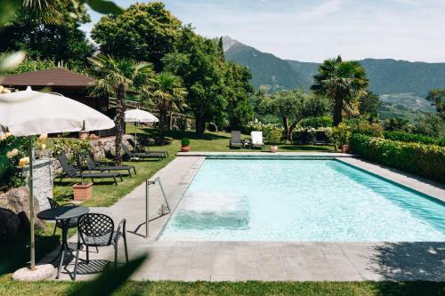 a swimming pool with a table and chairs and mountains at Alagundis Apartment Residence in Lagundo