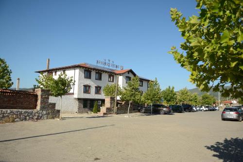 a white building with cars parked in a parking lot at Hotel Ulpiana, Ethno House in Gracanica