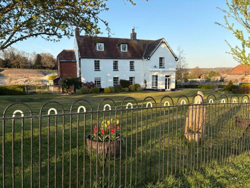 a white house behind a fence with flowers at Lower Bryanston Farm in Blandford Forum
