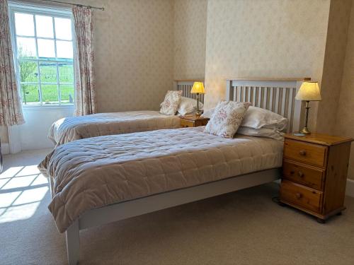 a bedroom with two beds and a dresser and a window at Lower Bryanston Farm in Blandford Forum
