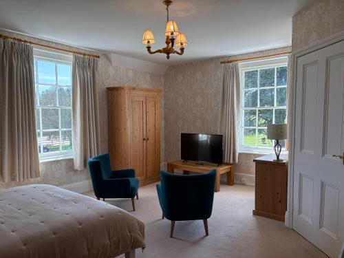 a bedroom with a bed and a television and chairs at Lower Bryanston Farm in Blandford Forum