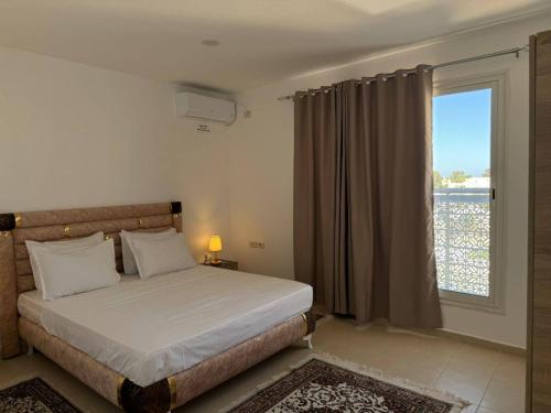 a bedroom with a bed and a large window at Résidence Elkhir Djerba in Djerba