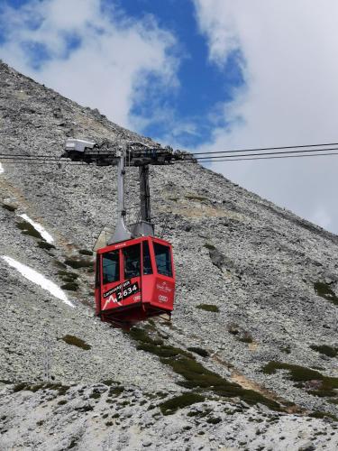a red cable car going up a mountain at Wellness Toliar Tatry in Stará Lesná