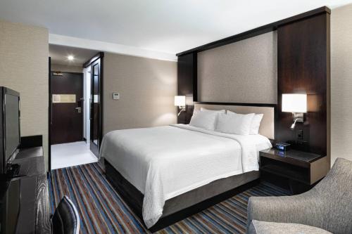 a hotel room with a large bed and a chair at Courtyard New York Manhattan/Times Square in New York